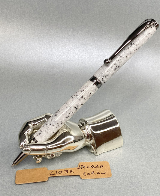 Speckled Corian pen with gun metal plated fittings on a chrome plated stand in the shape of a hand