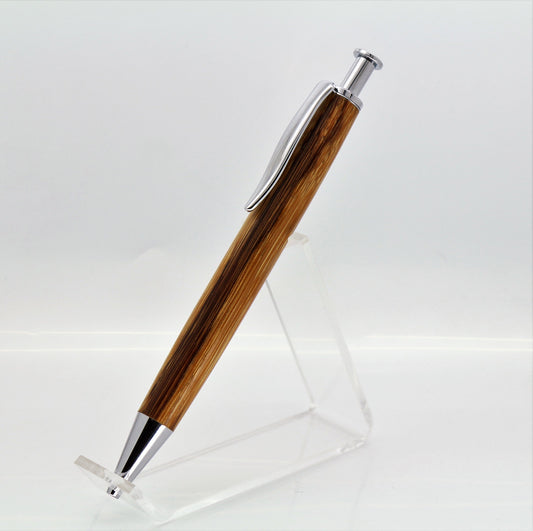 A hand made pen standing up at a 45 degree angle to the right, this a a longwood pen with no center band made in in Serpent wood allowing the wood to be shown off in all its glory. It has a click style top button to click the nib out.  All the fittings are Nickel plated fittings giving a nice sleek look.