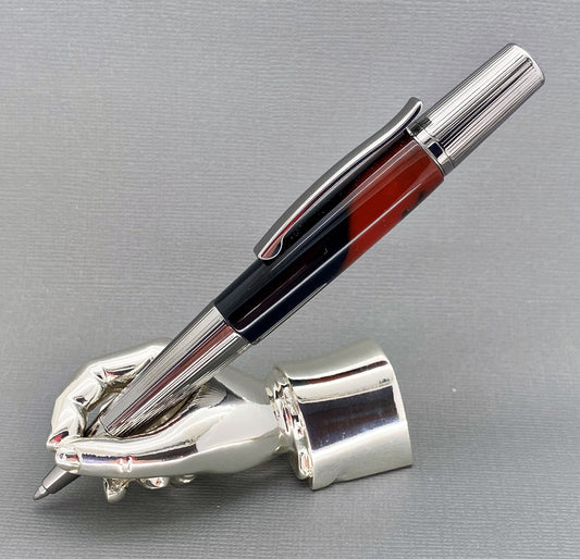 A right hand shaped metal base shown holding a handturned red/black acrylic pen as you would hold it to write with.