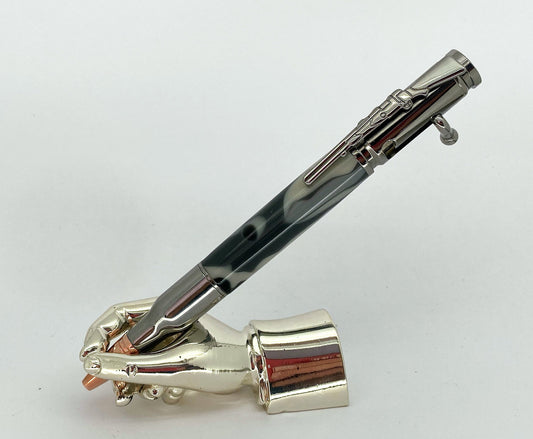 A right hand shaped metal base holding a handturned Grey cammo acrylic Bolt action pen as you would hold it to write with.