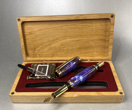Open lidded Oak box showing a Purple & red stripe effect Acrylic Fountain pen the pen has Gold plated fittings