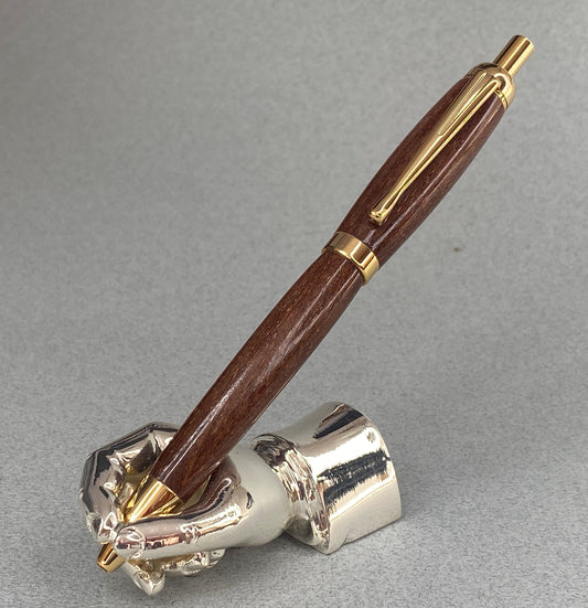 A right hand shaped metal base shown holding a handturned Red Luan wood pen as you would hold it to write with.