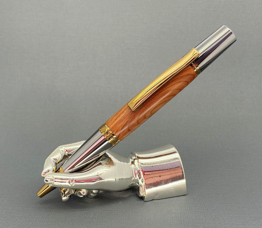 A right hand shaped metal base shown holding a handturned English Yew wood pen as you would hold it to write with.