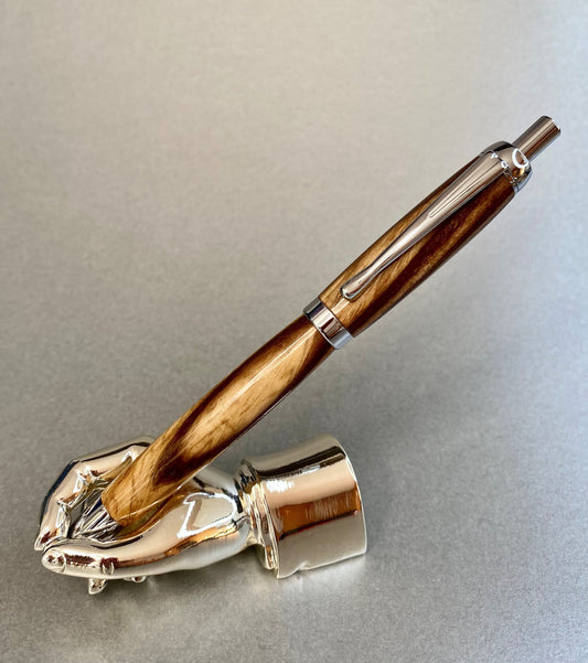 A right hand shaped metal base shown holding a handturned Black Ash wood pen as you would hold it to write with.